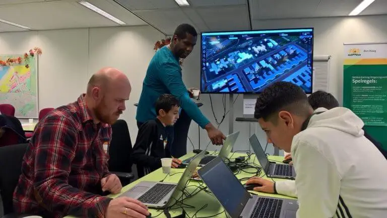 Leerlingen spelen CARRIÈRE in een lokaal op laptops en een groot scherm