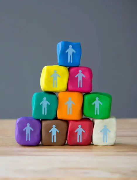 Een piramide van gekleurde blokjes met poppetjes als symbool voor teamopbouw